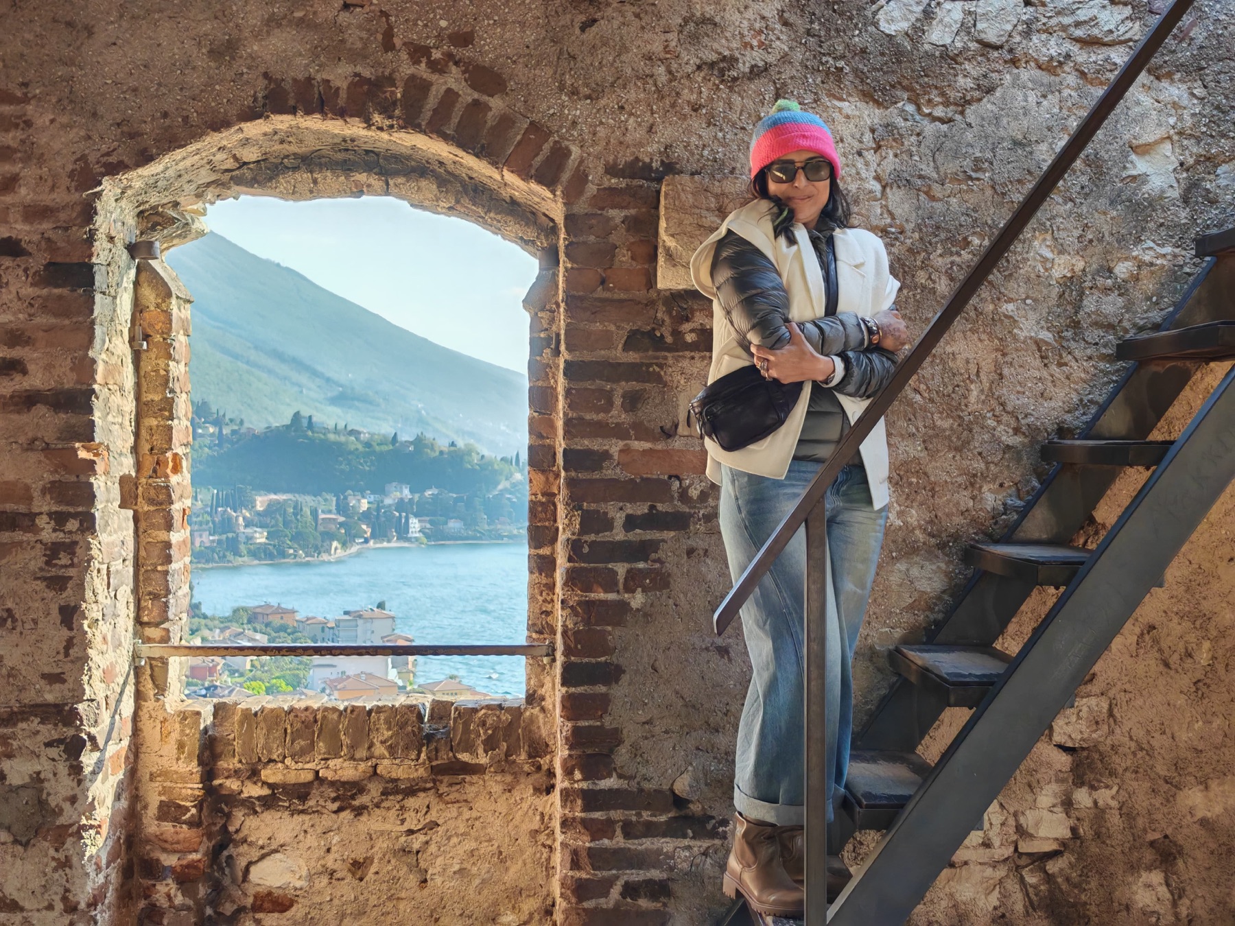 Pallavi on a castle stair above Lake Garda, a stone window behind her