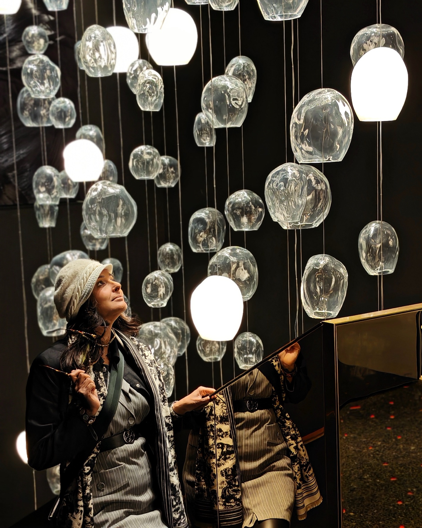 Pallavi beneath a field of hand-blown glass pendants, installed