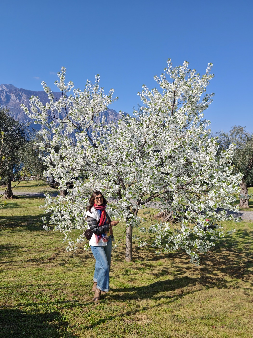 Pallavi beneath a blossoming tree with mountains behind