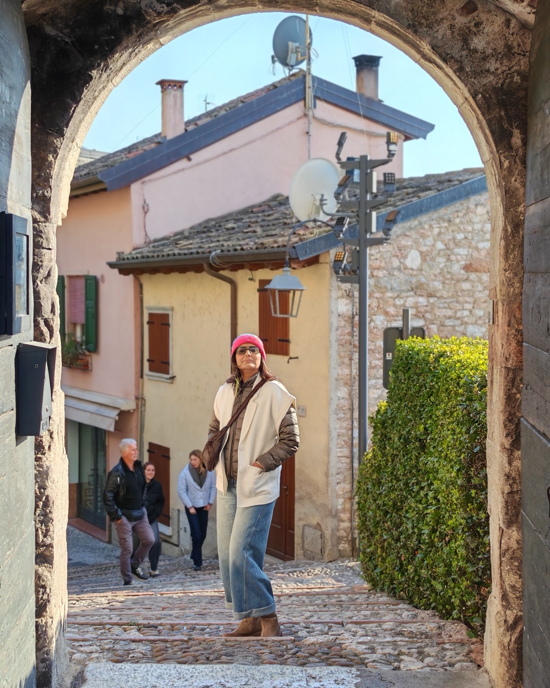 Pallavi walking through a stone archway in a village
