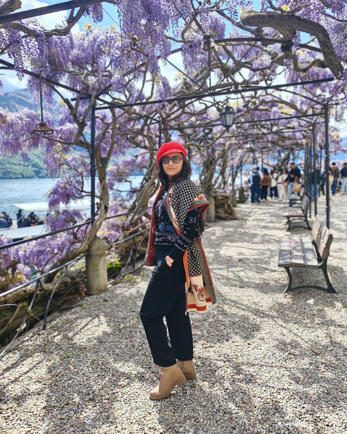 Pallavi under a wisteria pergola on a lakeside promenade