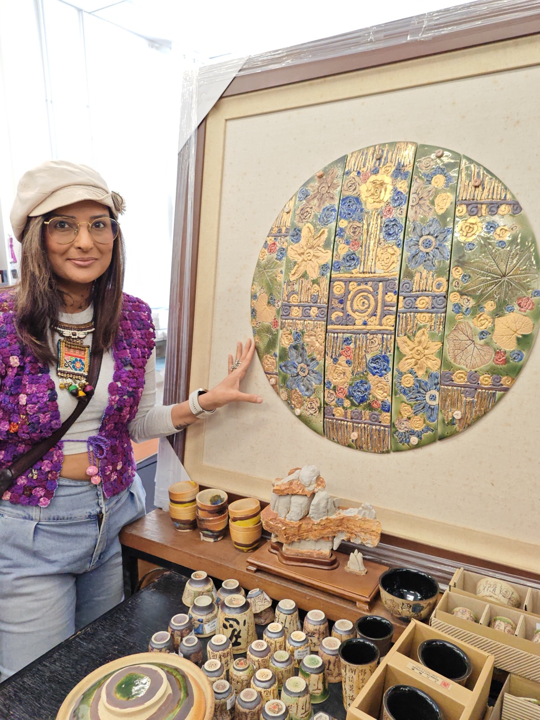 Pallavi beside a round mosaic artwork of gold and blue