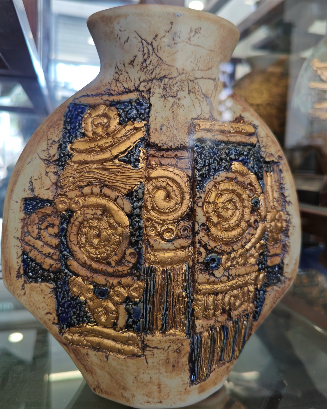 A carved vase with coiled gold and indigo relief
