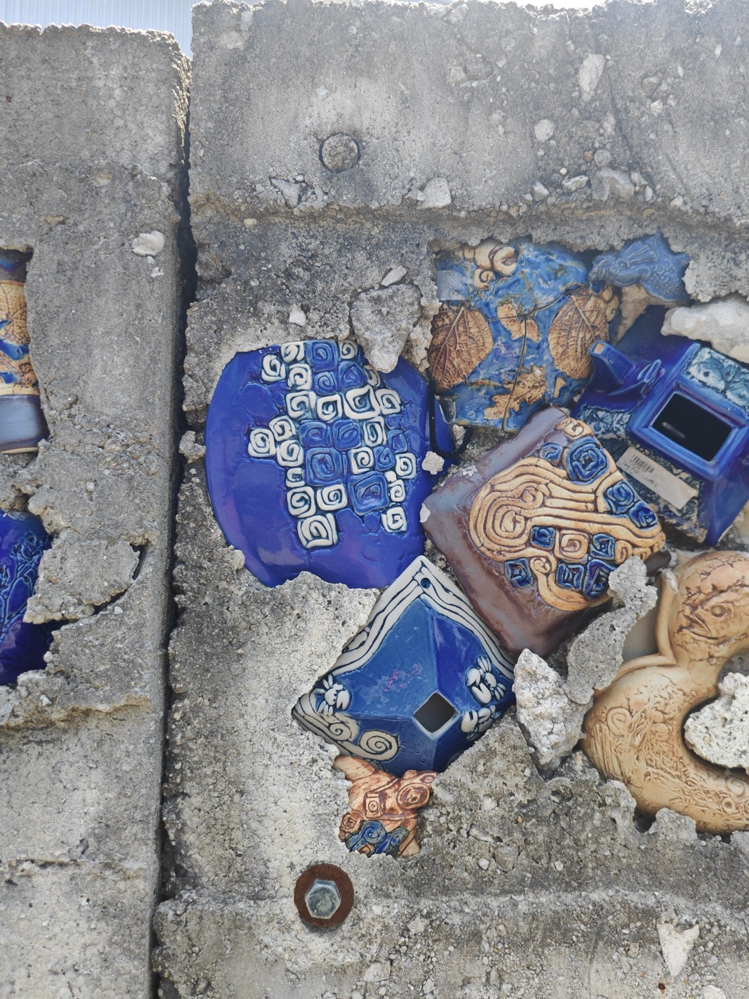 Fragments of glazed ceramics set into a concrete wall