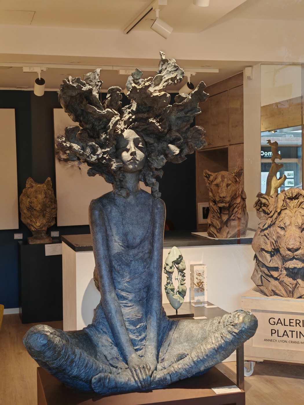 A bronze seated figure in a gallery of sculpture