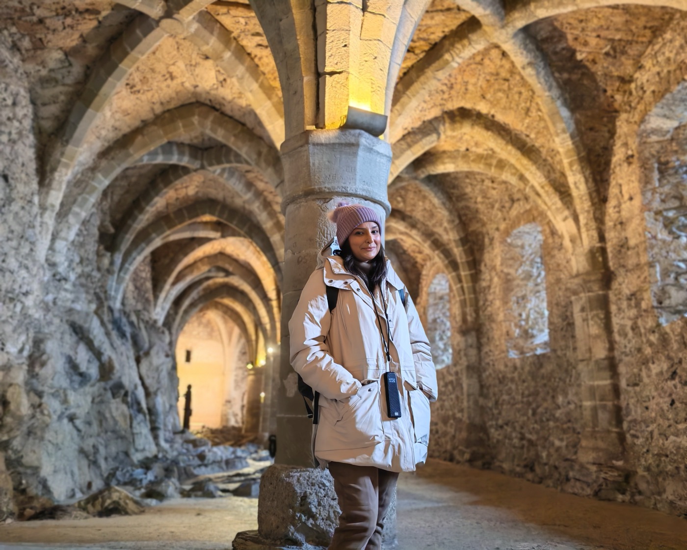 Pallavi beneath the vaulted stone columns of a castle undercroft