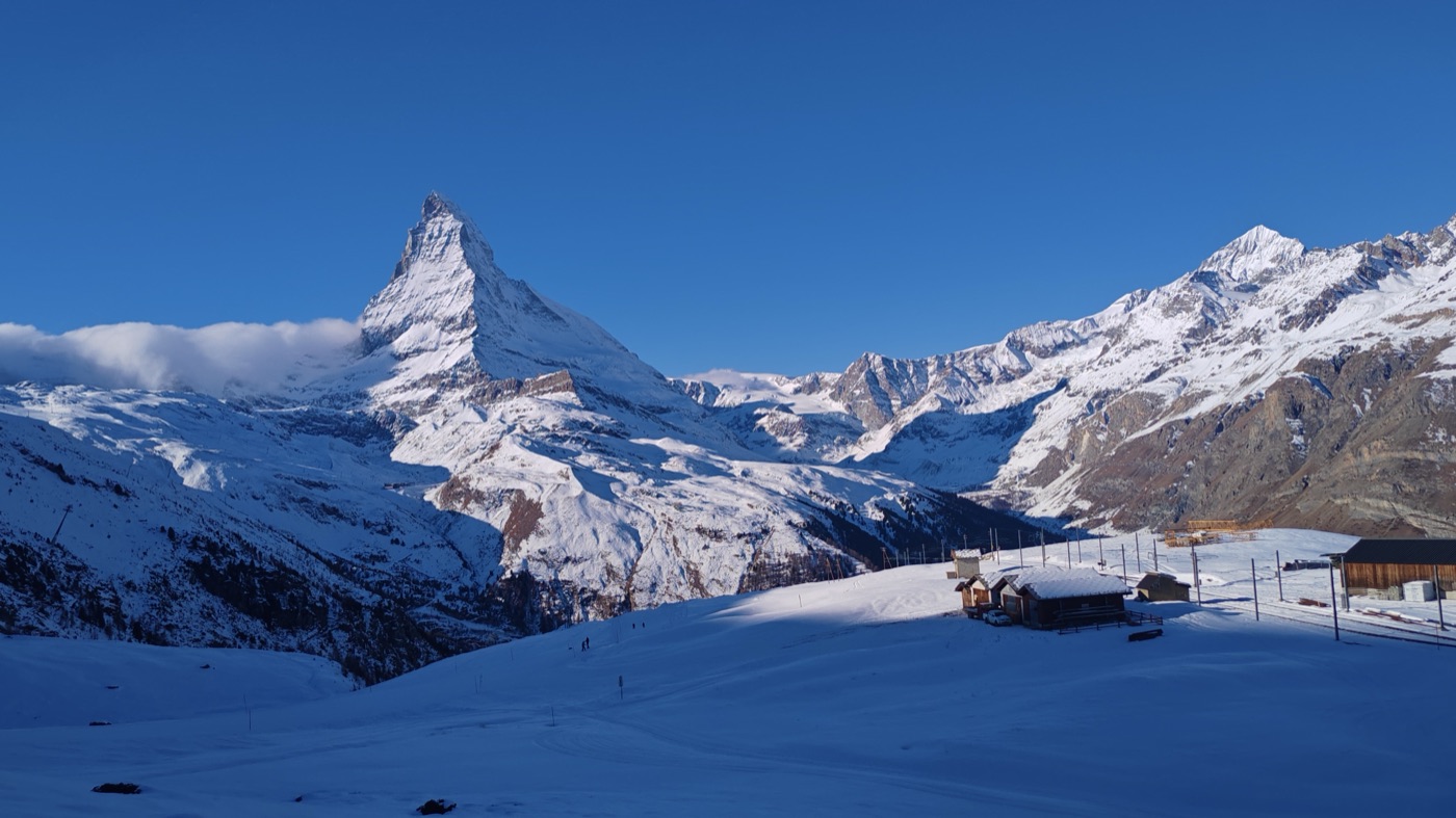 The Matterhorn above snowed-in huts under a blue sky